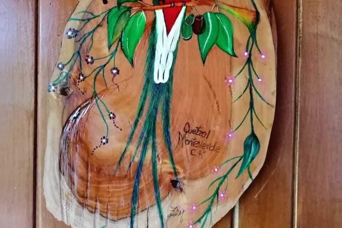 A wooden piece with a painted bird on a branch.