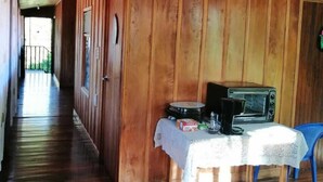 A wooden interior with a hallway leading to a door, a table with a coffee maker, and a small dog. - Sofi's Hostel Monteverde (Sierra)