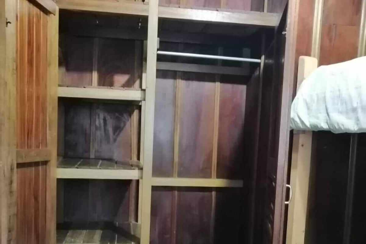A room with a bunk bed and a wooden wardrobe with multiple shelves.