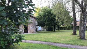A stone building with a door and windows, surrounded by a grassy area and trees. - 3 Bedroom  character property (L'Âge)