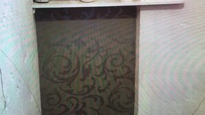 A room with a patterned wallpaper, a white shelf with a vase and a small decorative item, and a patterned carpet. - 3 Bedroom  character property (L'Âge)