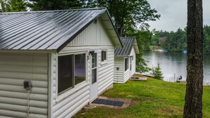 Une rangée de chalets en rondins au bord d’un lac, avec une jetée et un bateau.