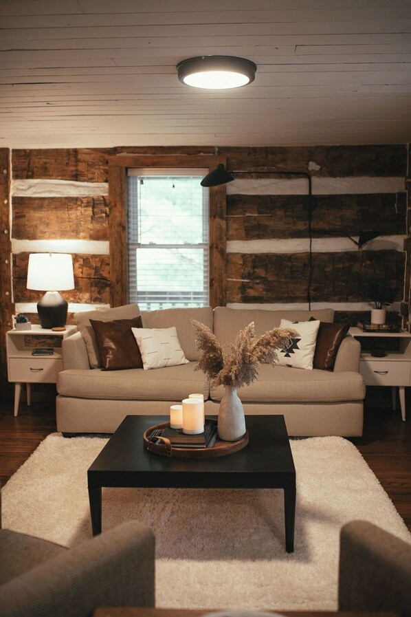 A cozy living room with a sofa, a coffee table with candles, and a vase with dried flowers.