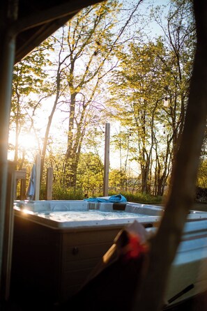 A hot tub in a wooded area with trees and sunlight. - Beautiful and Historic Log Cabin: cozy, quiet, huge hot tub! Quiet getaway! (Goshen)