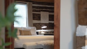 A bedroom with a bed, a nightstand, a lamp, and a ceiling fan. - Beautiful and Historic Log Cabin: cozy, quiet, huge hot tub! Quiet getaway! (Goshen)