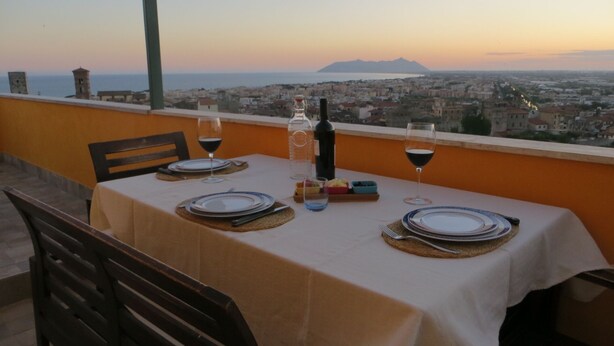 A table set for two with a view of a cityscape and mountains in the background. - Casa Martina Appartamento Panoramico (Terracina)