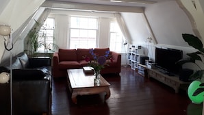Un salon chaleureux avec un canapé en cuir marron, une table basse en bois et un meuble pour la télévision.