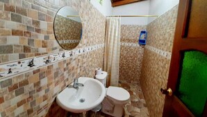 Une salle de bain avec un mur carrelé, un lavabo, des toilettes et un miroir.