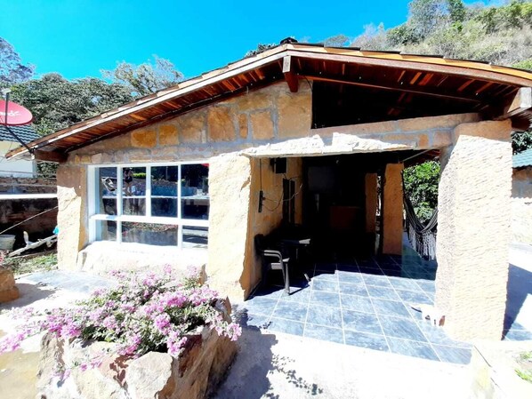 Un edificio de piedra con un patio empedrado, una ventana y una pequeña mesa.