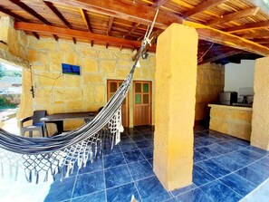 Una hamaca en un espacio al aire libre cubierto con paredes de piedra y suelo de baldosas.