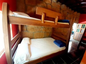 Cozy retreat with a single bunk bed, featuring a comfortable mattress and pillows, situated against a stone wall.