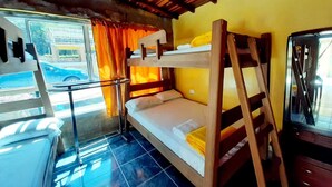 Une chambre avec un lit superposé, une échelle en bois, une petite table et une fenêtre avec des rideaux.
