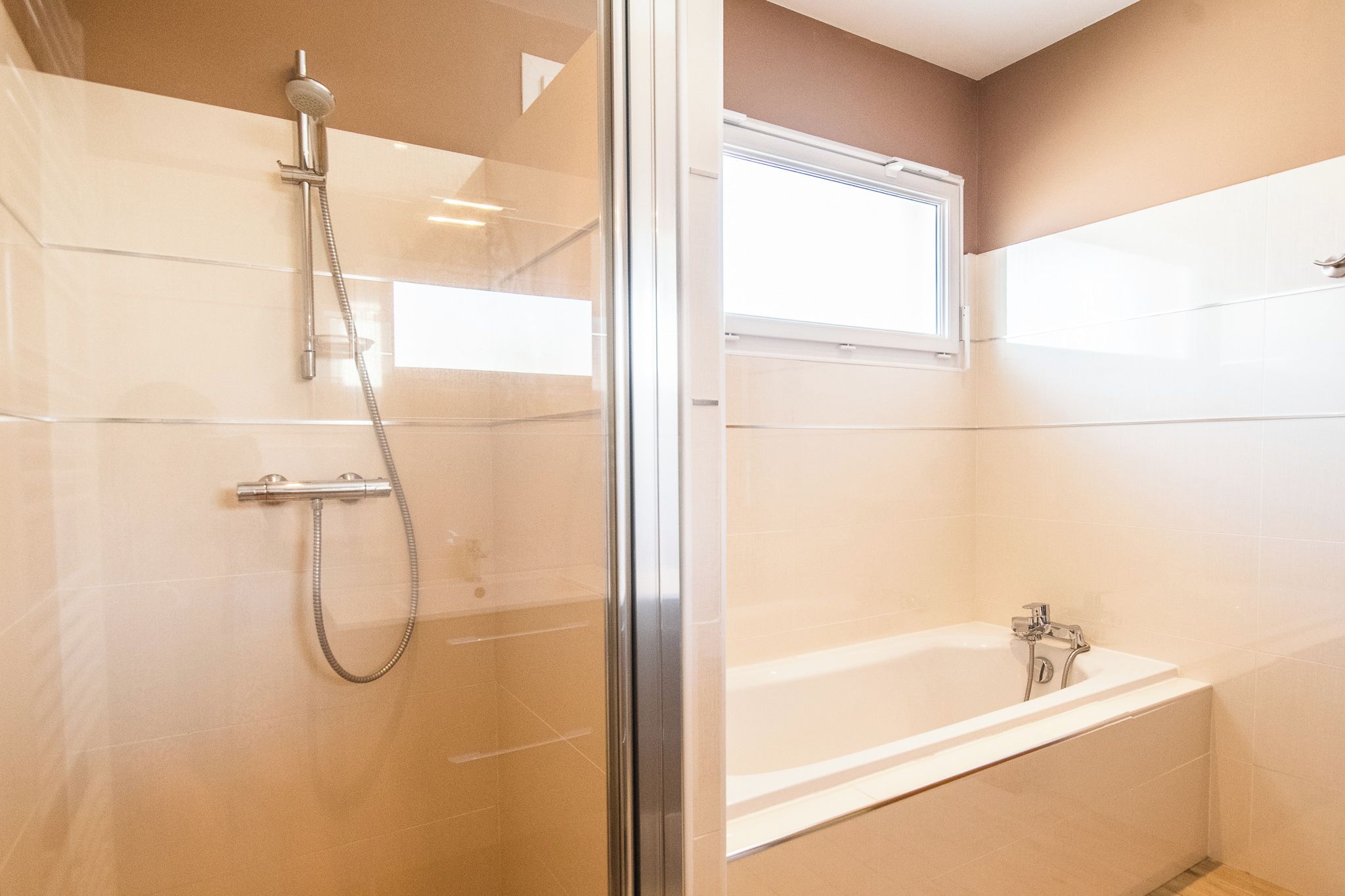 Un baño moderno con ducha de vidrio, una bañera independiente y un ventanal que proporciona luz natural.