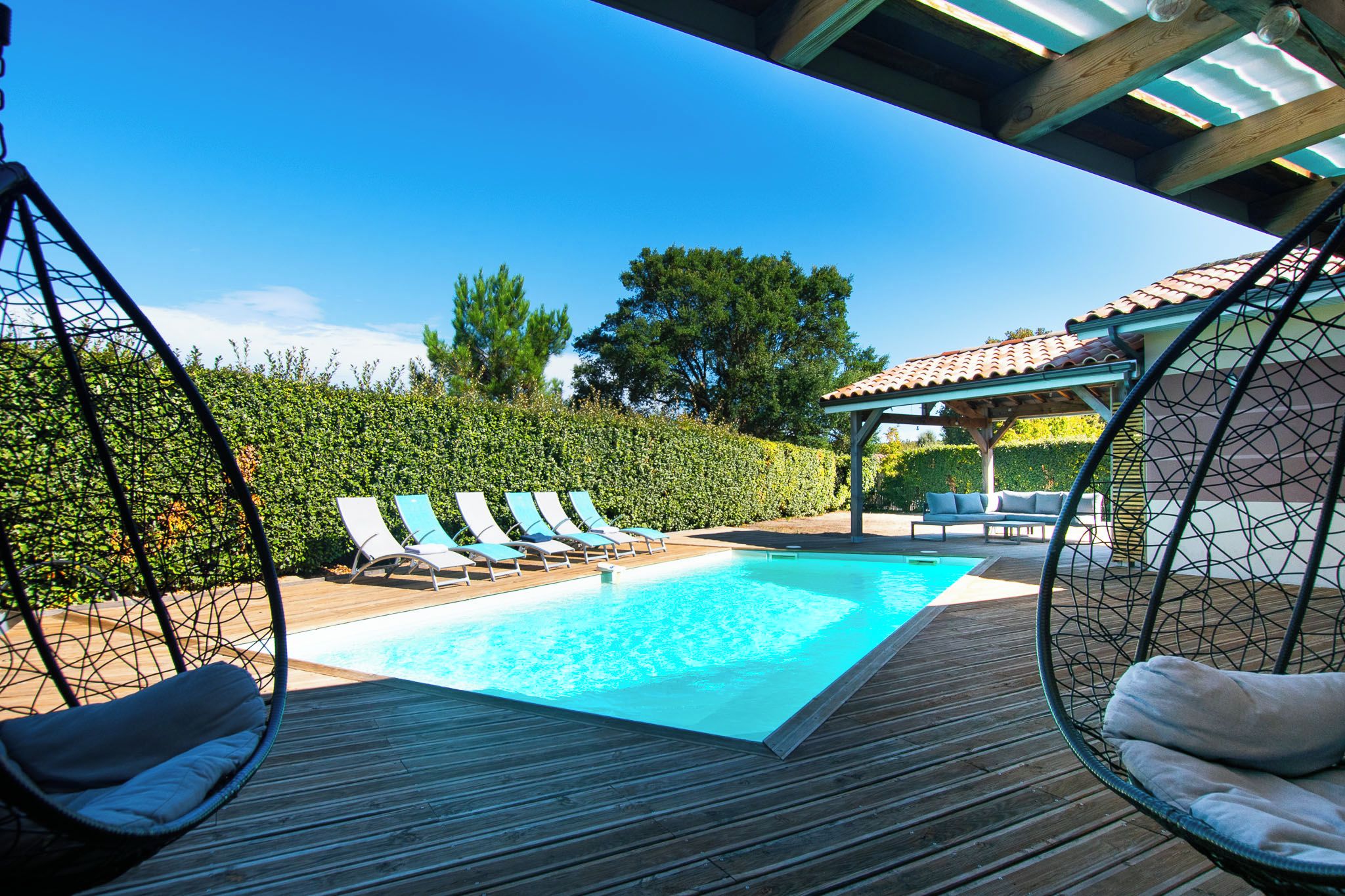 Una piscina con sillones de descanso y una pérgola.