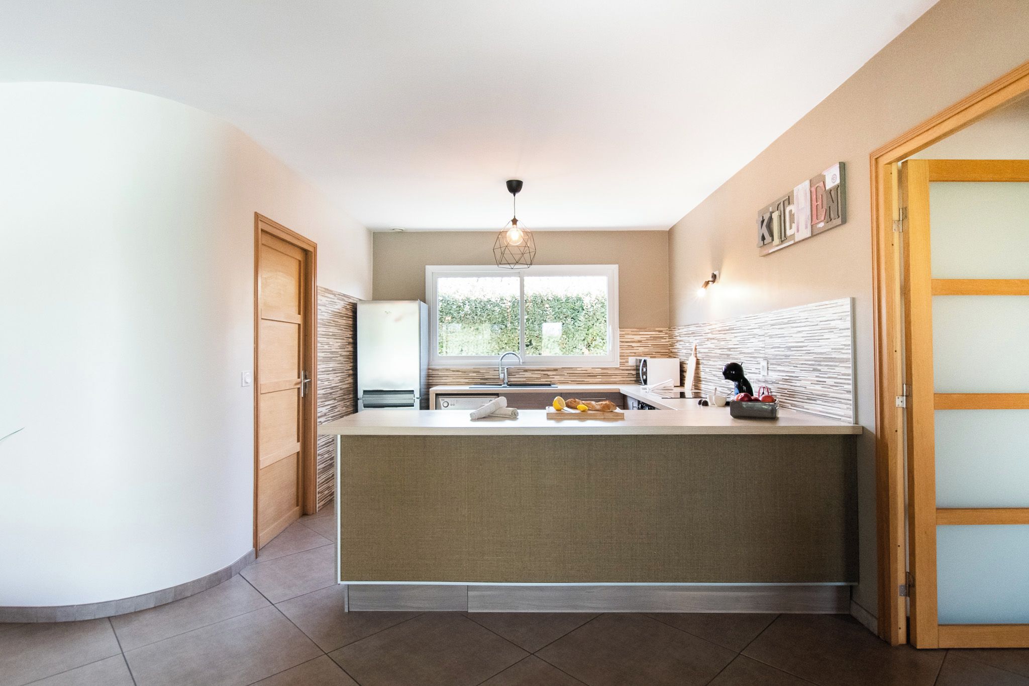 Una cocina moderna con una isla central, horno empotrado y ventana que proporciona luz natural.
