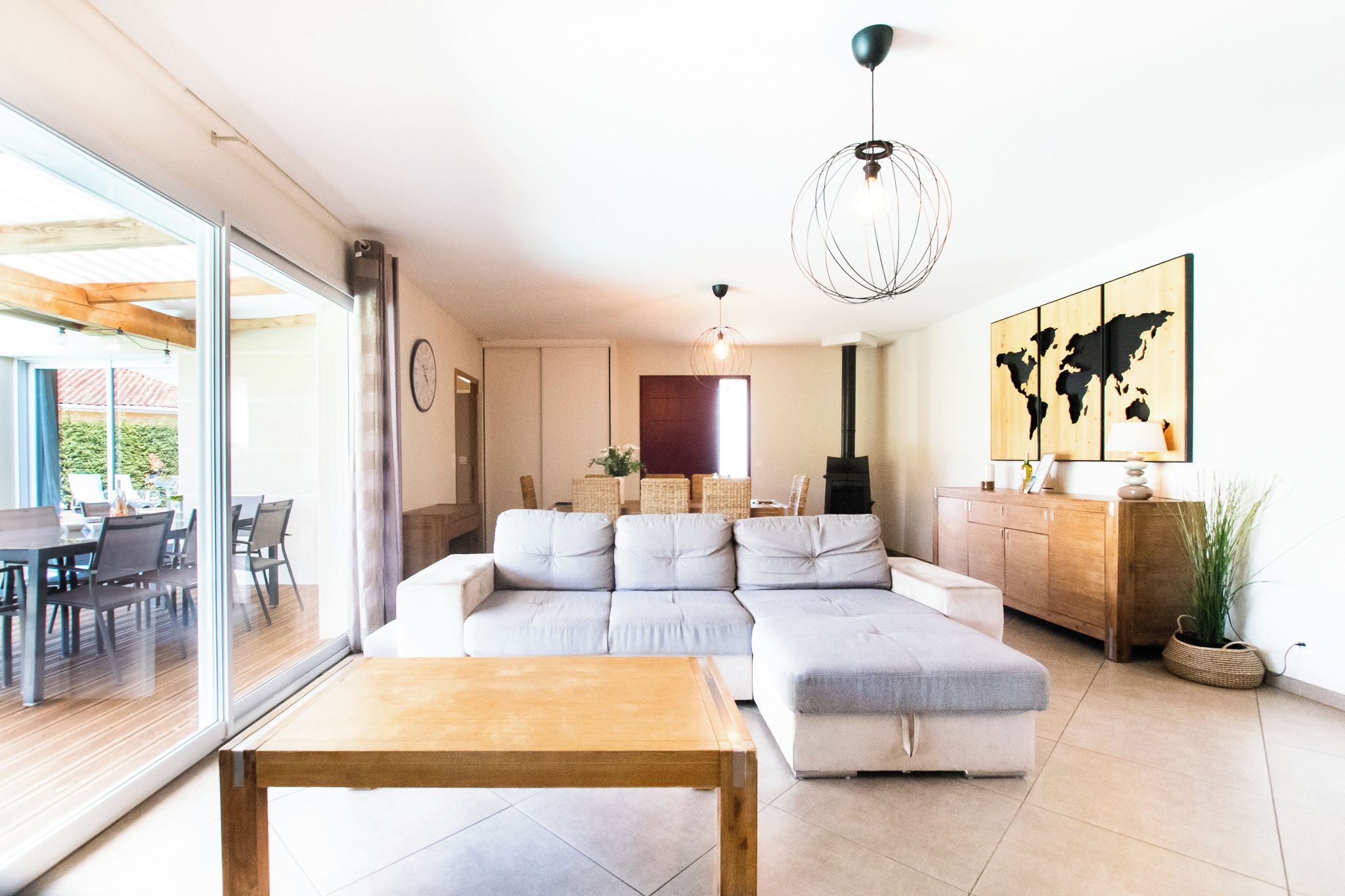 Una sala moderna con un sofá modular, una mesa de centro de madera y un comedor con sillas y una mesa.