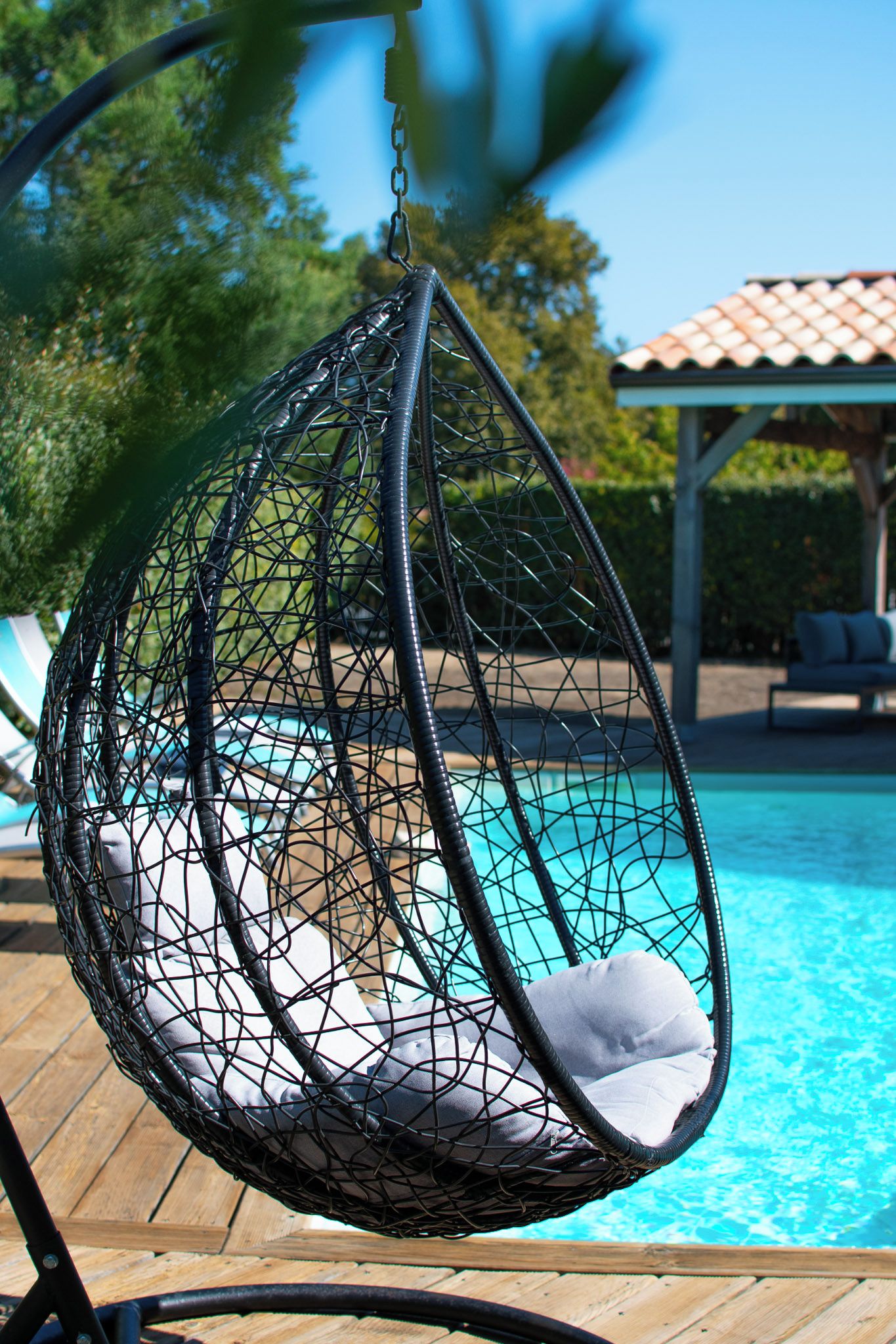 Uma cadeira rede com almofadas ao lado de uma piscina.