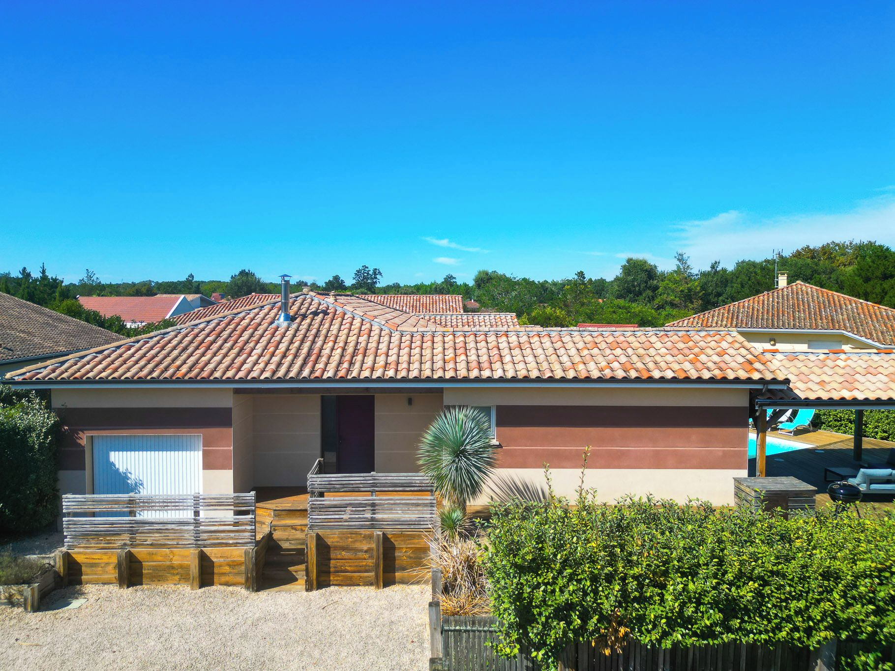 Un edificio residencial con techo de tejas, un porche cubierto y una piscina al fondo.