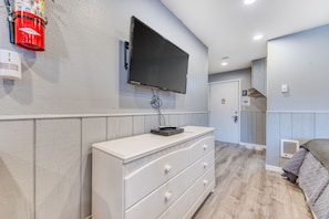 Enjoy a comfortable stay in this stylish room featuring a flat-screen TV, dresser, and wooden floor.