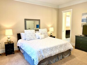 A bedroom with a bed, two bedside tables with lamps, a dresser, and a mirror on the wall.