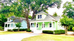A two-story house with a porch, a covered front porch area, and a front yard with a lawn and trees.