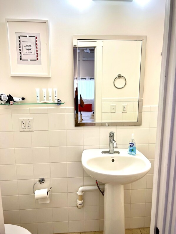 A bathroom with a white sink, a mirror, a framed sign on the wall, and toiletries on a shelf. - Marfa House El Balcon, in the heart of Marfa with direct balcony access (Marfa)
