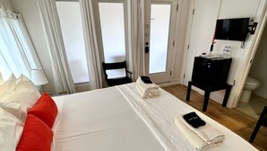 A hotel room with a large bed, two pillows, a desk with a chair, a television, and a bathroom. - Marfa House El Balcon, in the heart of Marfa with direct balcony access (Marfa)