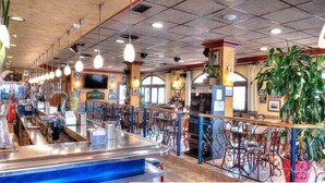 Un bar con mostrador, estanterías llenas de objetos varios y una zona de estar con sillas y mesas.