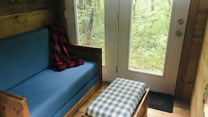 Et interiør af en træhytte med en blå sofa og en bænk.