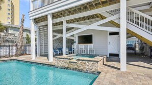 A covered outdoor swimming pool area with stone walls and a white building structure.