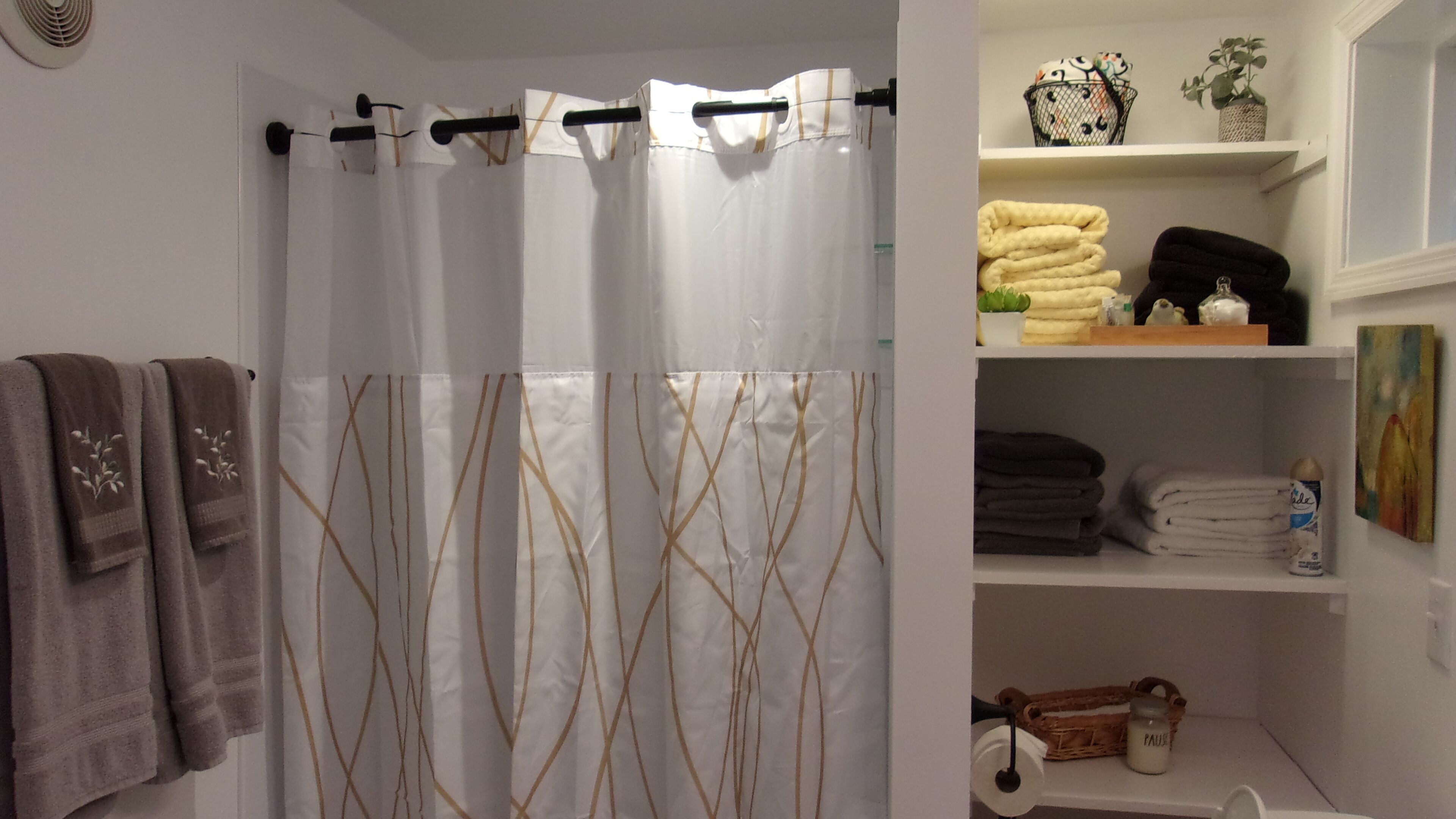 Ein Badezimmer mit Duschvorhang, Handtüchern und einem Ablagefach für Pflegeprodukte.