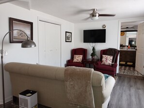 A living room with a beige sofa, two red armchairs, a ceiling fan, a flat-screen TV, and a small plant. - The Commuter's Dream. This location is close to you destination. (Chattanooga)