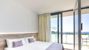 Ein modernes Hotelzimmer mit einem großen Bett, Meerblick und einer Glasschiebetür zu einem Außenbereich.