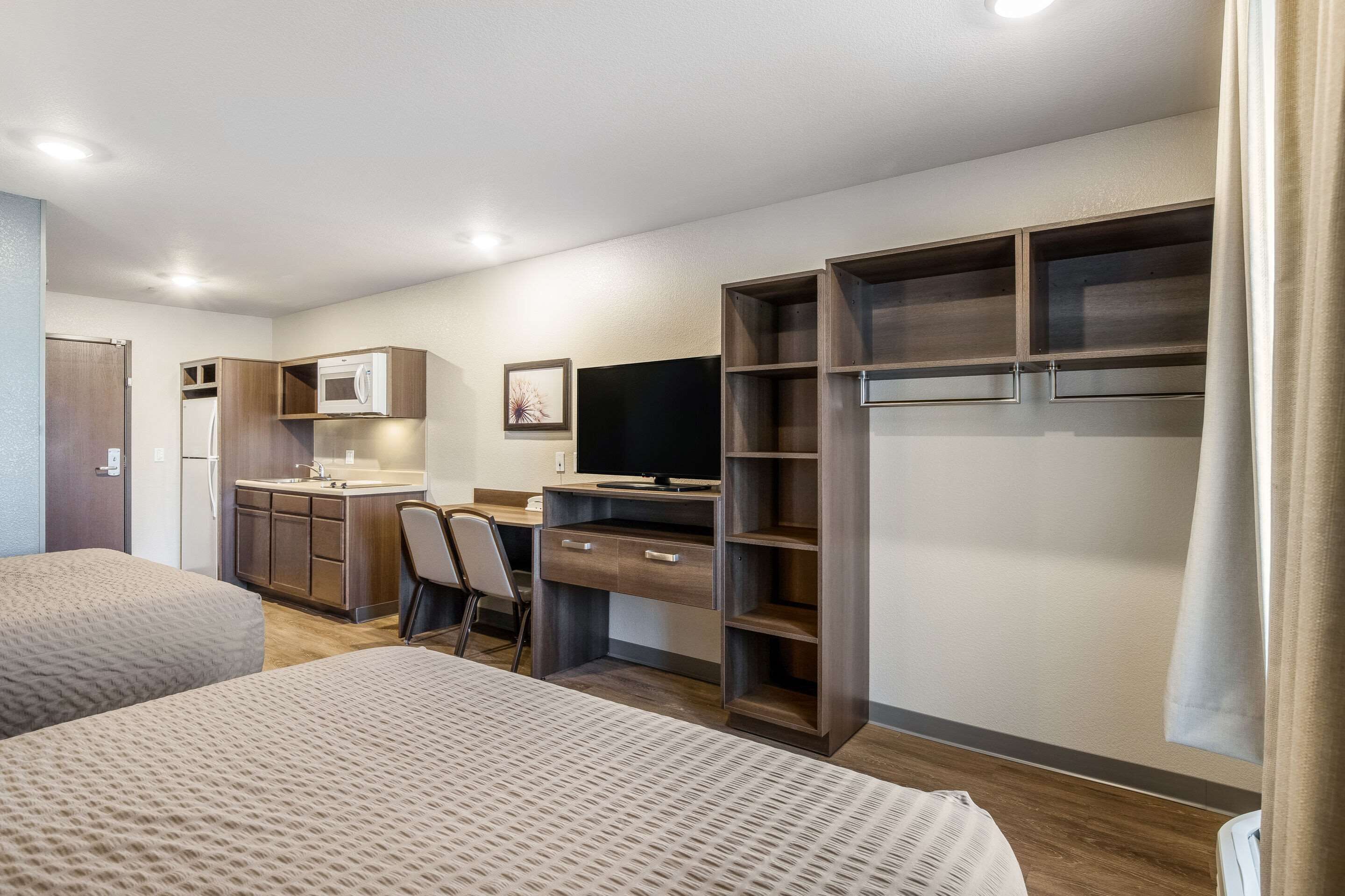 Une chambre d’hôtel compacte comprenant un coin cuisine, un lit, un bureau et un téléviseur.