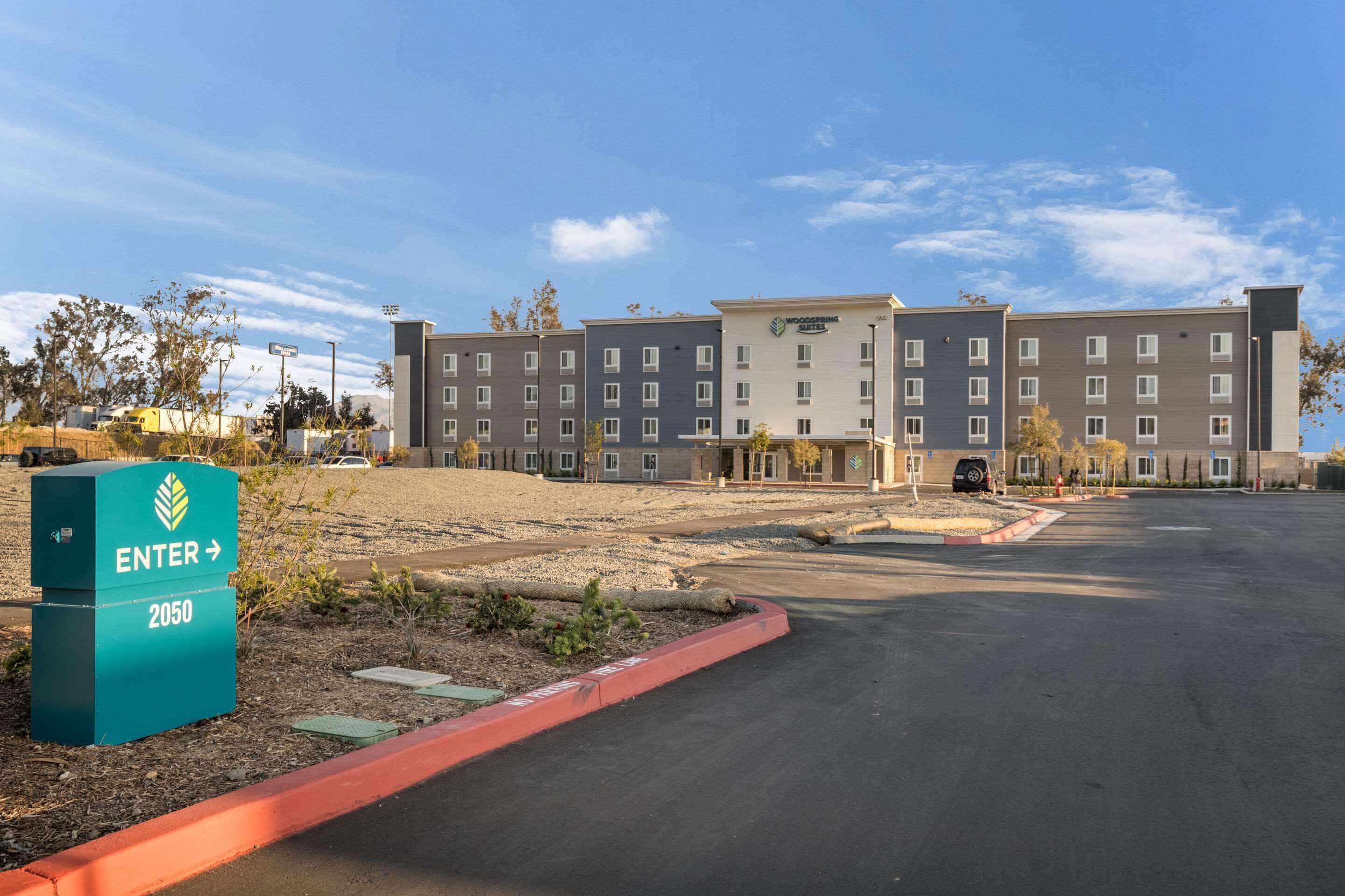 Un hôtel à plusieurs étages, doté d’un design moderne, comprenant un grand parking et un espace d’entrée aménagé.