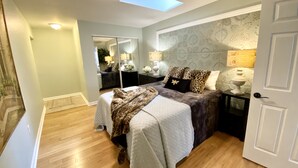 A bedroom with a bed, a nightstand, a mirror, and a skylight. - The Paris Loft in the heart of downtown (Safety Harbor)