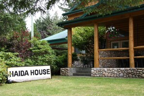 A wooden cabin named "Haida House" with a stone foundation, surrounded by lush greenery and trees.