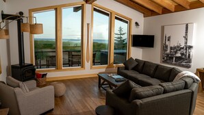 Una sala de estar acogedora con un ventanal grande, chimenea, sofá y televisor de pantalla plana.