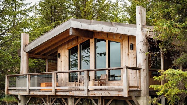 Una cabaña de madera con balcón, ventanas amplias y terraza.