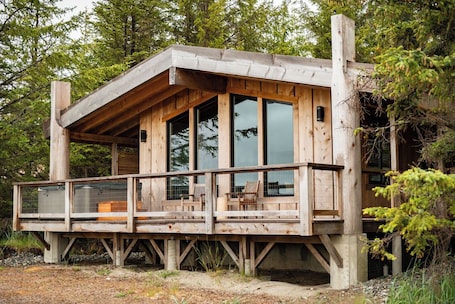 A wooden cabin with a balcony, large windows, and a deck.