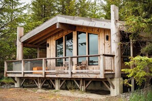 Una cabaña de madera con balcón, ventanas amplias y terraza.