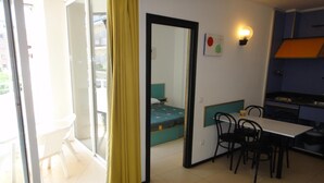 A compact room with a bed, a dining table with chairs, a small kitchenette, and a sliding glass door leading to an outdoor area. - Apartments very close to the beach. Ref.LLORET SUN-24 (Lloret de Mar)