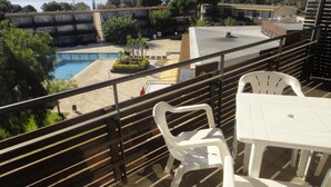 A balcony with a view of a swimming pool, outdoor seating, and a distant view of the sea. - Modern apartments with pool. Ref. Comtat Sant Jordi -24 P (Platja d´Aro)
