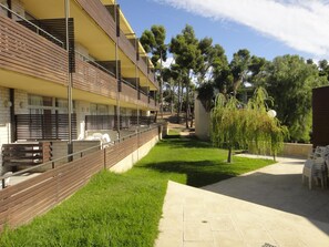 A hotel with a modern design, featuring balconies with wooden railings and a grassy courtyard.