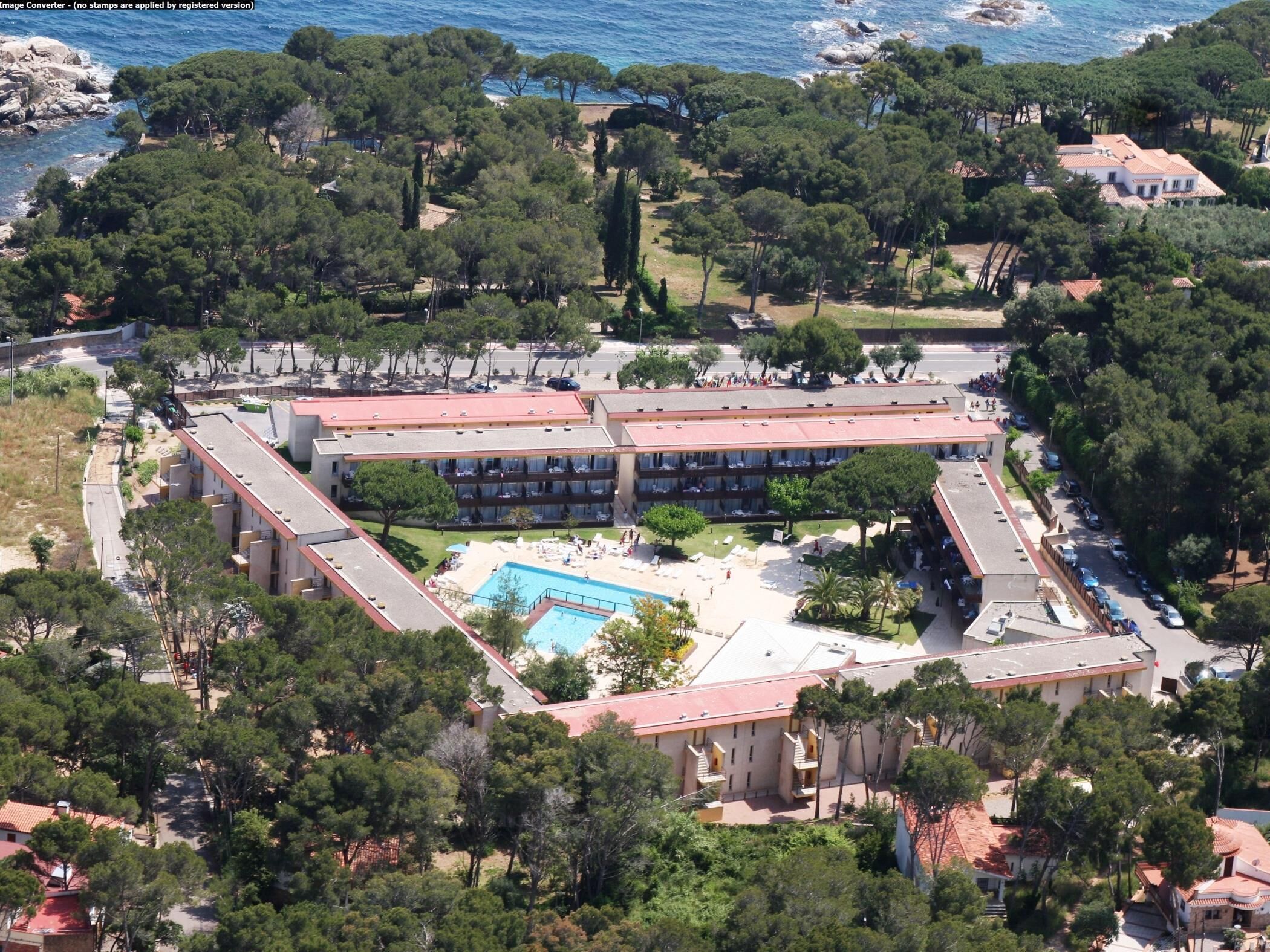 Vista aérea de un hotel con un patio central, varias construcciones y una piscina.