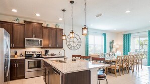 A modern kitchen with dark wood cabinets, stainless steel appliances, and a large island.