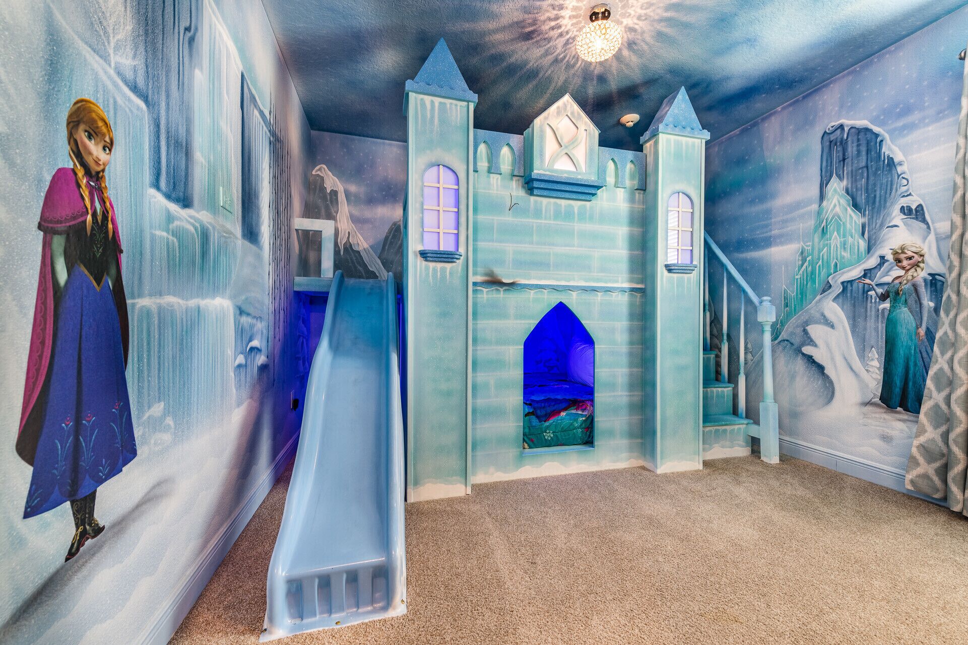A room with a castle-themed mural, a slide, and a large window.