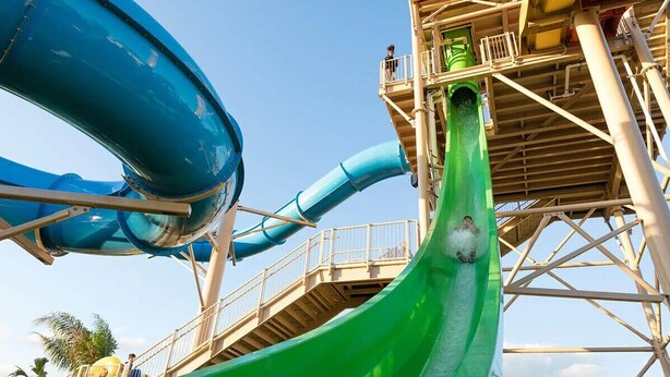 A water slide structure with multiple lanes and a platform with railings.