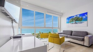 Un soggiorno moderno con una grande finestra vista spiaggia, un divano e un'area pranzo.