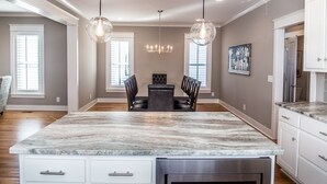 Una cocina amplia con una isla grande, iluminación colgante y un comedor con mesa y sillas.
